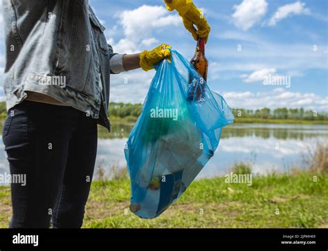 Une jeune femme en gants jaunes recueille les ordures abandonnées dans