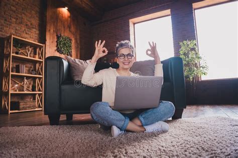 Beautiful Mature Woman With Grey Hair Sitting Cross Legged Indoors Enjoying Leisure Using