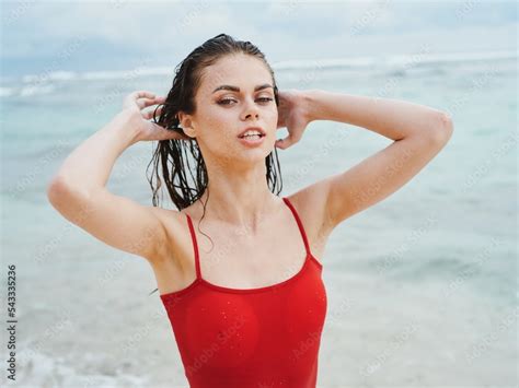 Sexy Woman In Red Swimsuit On Ocean Beach With Wet Hair Covers Face With Hands Sunscreen Stock