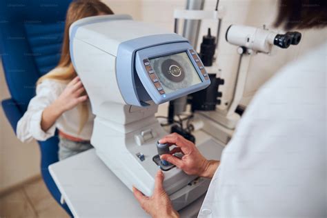 Focused picture of experienced doctor using slit lamp while checking