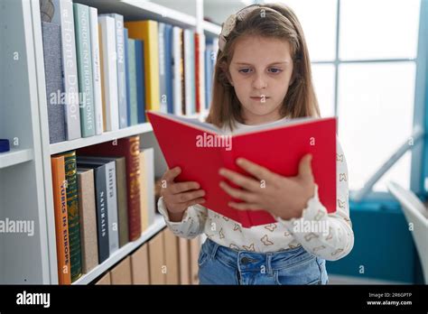 Adorable Blonde Girl Student Reading Book At Classroom Stock Photo Alamy