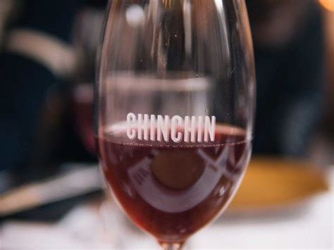 A Wine Glass With The Word Chinchinn Written In White Ink On It Sitting