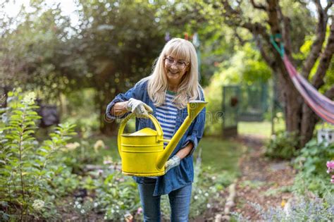 Mature Woman Watering Plants In Her Garden Stock Image Image Of Woman