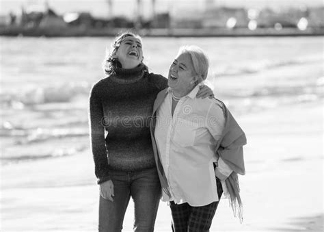 Portrait Of Beautiful Older Mom And Mature Daughter Walking On The Beach At Autumn Sunset Stock