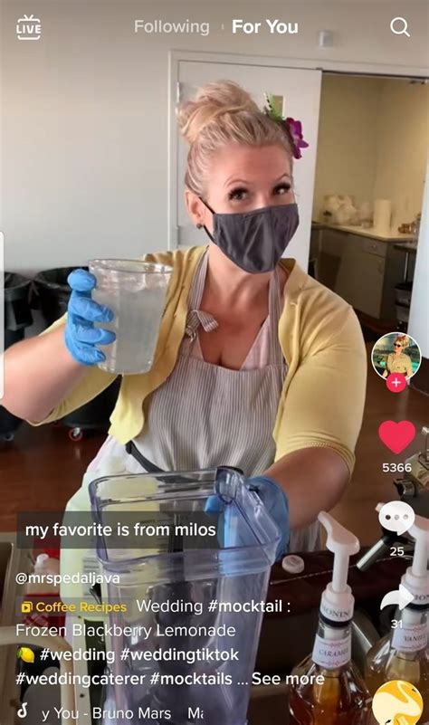 a woman wearing a face mask and gloves holding a blender with liquid in it