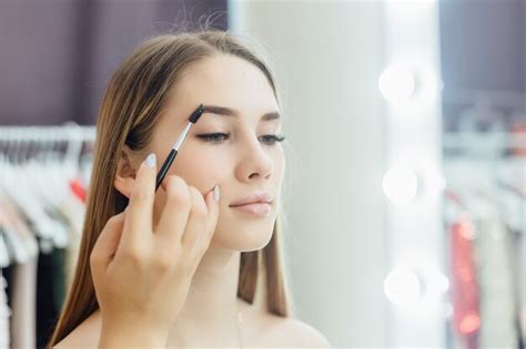 La Jeune Belle Fille Blonde Fait Un Maquillage Naturel Devant Le Miroir