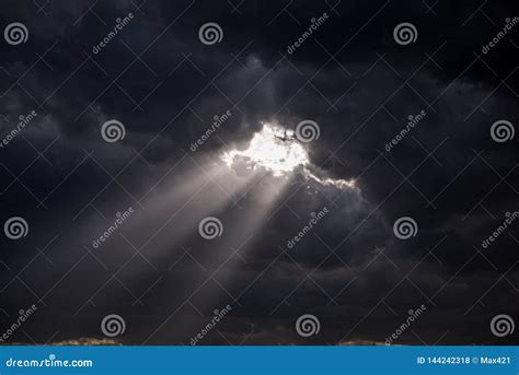 Beaming Rays Of Light Break Through Dark Menacing Clouds Stock Photo