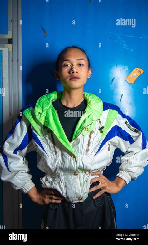 A Gay Asian Man Posing In A Tracksuit In Front Of A Blue Locker During A Night Break Stock Photo