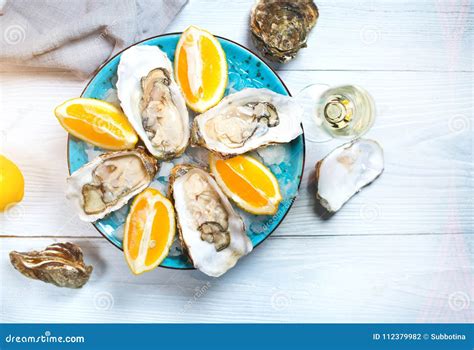 Fresh Oysters Close Up On Blue Plate Served Table With Oysters Lemon And Champagne In