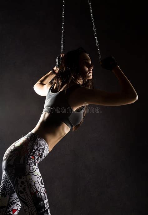 Strong Muscular Woman With Iron Chain On Dark Background In The Beam Of