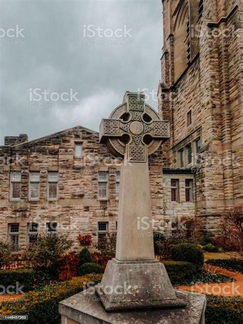 Stone Cross Monument Stands Tall In Front Of Old Historic Church