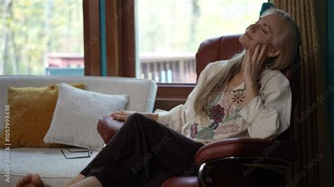 A Woman With Long Blonde Hair Sits In A Brown Recliner Chair Eyes
