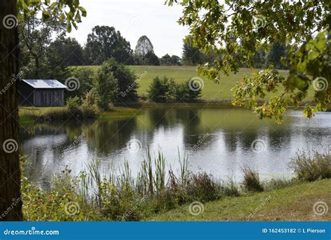 The High Mountain Pond Is Surrounded By Pastures Of Green Grass And