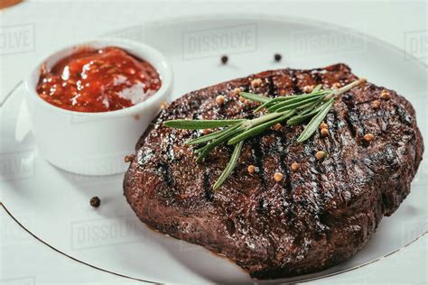 Close Up View Of Grilled Steak With Pepper Rosemary And Sauce On White