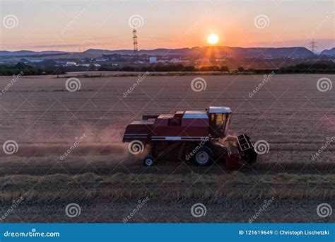 Aerial View Of Combine Harvester Harvesting An Oats Crop At Sunset