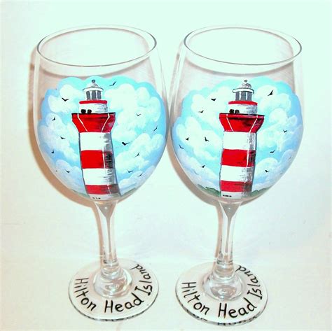 Two Wine Glasses Painted With Lighthouses And Words On The Bottom One Is Red And White