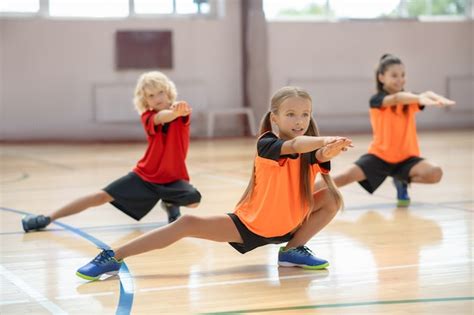 Hacer ejercicio tres niños haciendo ejercicio en el gimnasio y mirando