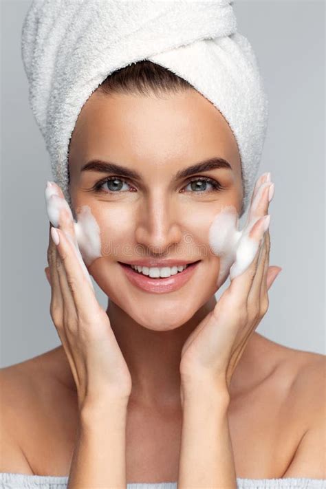 Happy Young Woman With Bath Towel On Her Head Takes Care Of Her Skin Face Applies Cleansing