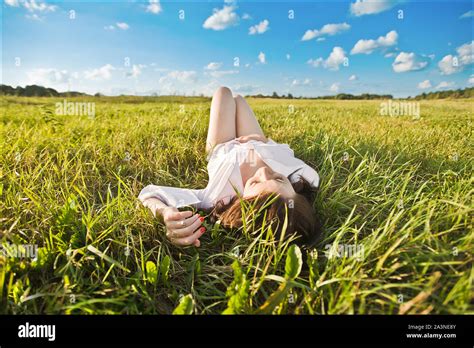 The girl lies on the grass. Happy smiling beautiful girl lying among grass and flowers. on a ...