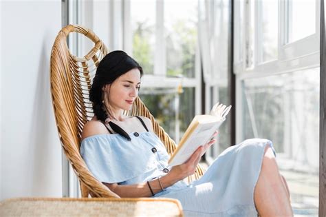 Belle Jeune Femme Assise Sur Une Chaise En Lisant Un Livre Photo Gratuite