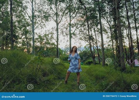 Lifestyle Image Of Woman With Long Dark Hair In Forest Wearing A Summer