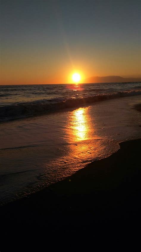 The Sun Is Setting Over The Water At The Beach