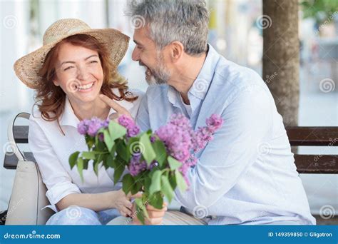 Happy Mature Couple Enjoying Their Time Together Sitting On A Bench On