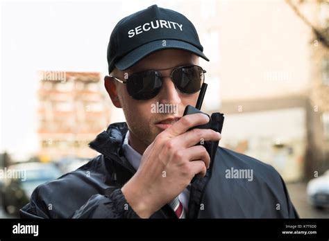 Portrait Of Young Male Security Guard Talking On Walkie Talkie Stock