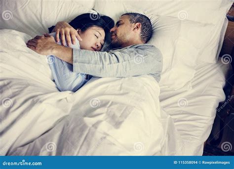 Snuggling Latin Gay Couple In Pajama On The Sofa Taking Hands And Sharing A Relaxing Moment Out