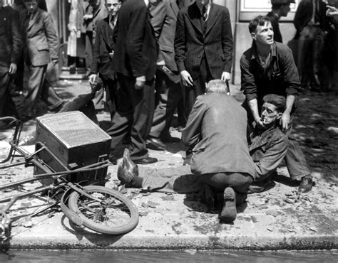 Лондонцы помогают на улице раненому во время бомбардировки — военное фото