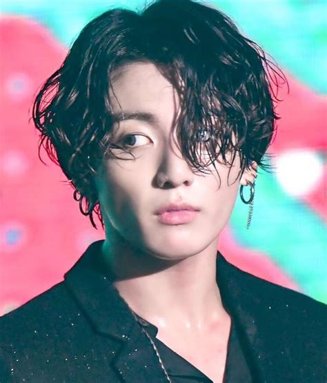 A Woman With Curly Hair And Piercings Standing In Front Of A Colorful