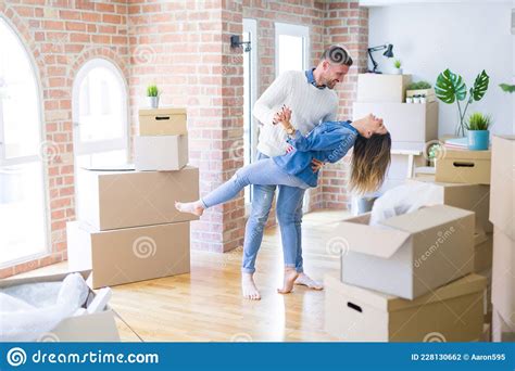 Young Beautiful Couple Dancing At New Home Around Cardboard Boxes Stock