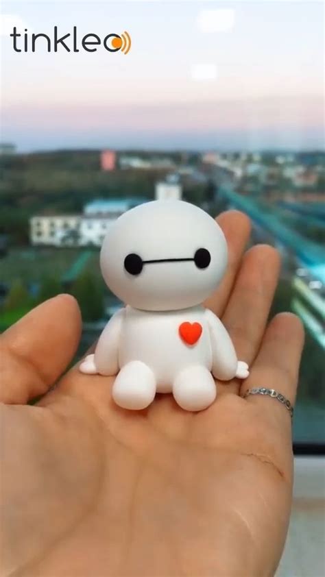 A Hand Holding A Small White Toy With A Red Heart On It S Chest