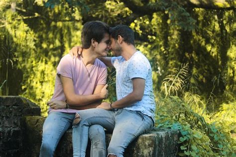 Una joven pareja de hombres gay besándose en el parque Foto Premium