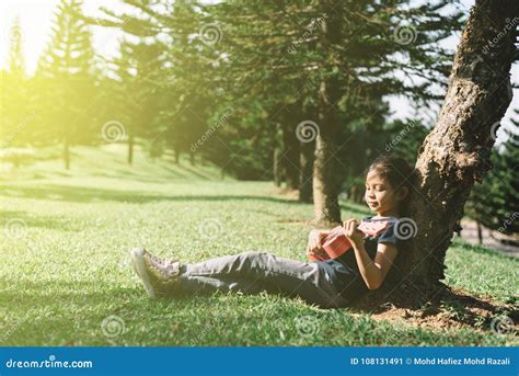 Young And Happy Asian Girl Playing With Ukelele Guitar At The Park In