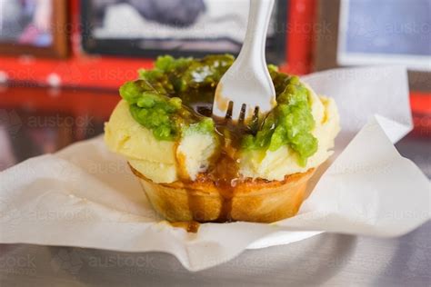 Image of Meat pie topped with mashed potato, peas and gravy - Austockphoto