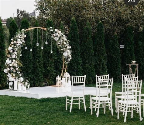 An Outdoor Ceremony Setup With White Chairs And Flowers