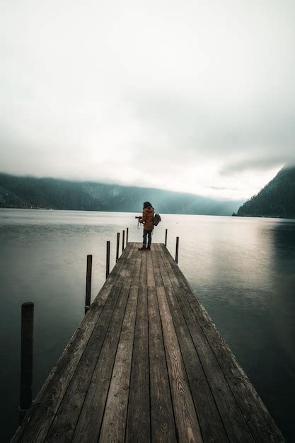 Premium Photo Rear View Of Man Standing On Pier Over Lake Against Sky