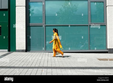 Asian Woman Dressed In Bright Yellow Clothes Walks Across Green