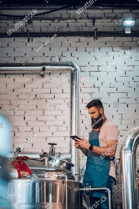 Portrait Of Brewery Worker Checking Fermentation Process And Using