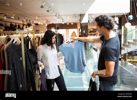 Shop Assistant Helping Female Customer Choose Top In Clothing Store