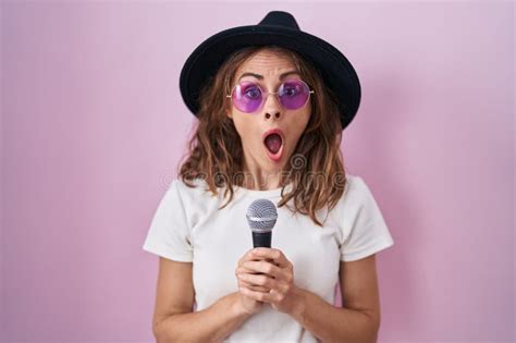 Beautiful Brunette Woman Singing Song Using Microphone Afraid And Shocked With Surprise And
