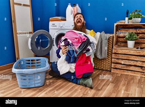 Redhead Man With Long Beard Putting Dirty Laundry Into Washing Machine