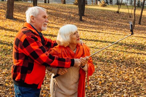 Positive Mature Couple Showing Tongues Laughing And Fooling Around While Taking Selfie Pictures