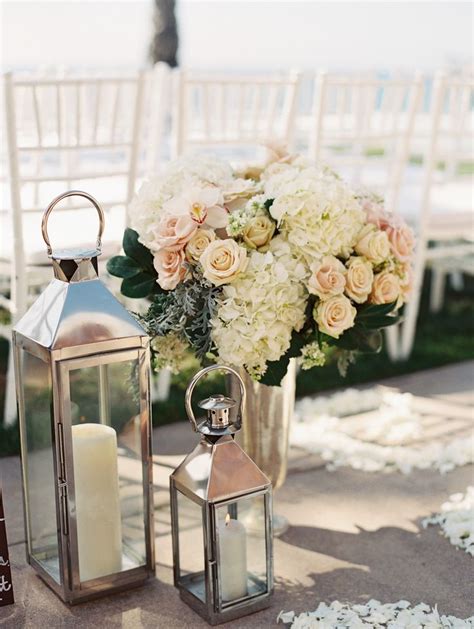 An Outdoor Wedding Setup With Candles And Flowers In Vases On The Side