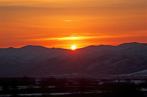 Premium Ai Image Blazing Winter Solstice Sunset Behind Silhouetted Hills