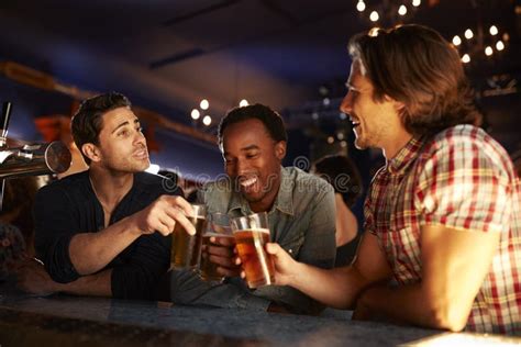 Grupo Dos Amigos Masculinos Que Bebem A Cerveja Na Barra Junto Foto De