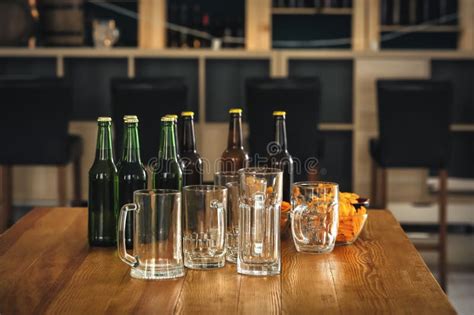 Bottles Of Beer With Glasses And Snack On Table In Bar Stock Photo