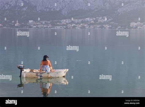 Man Relaxed Fishing In A Small Boat On Kotor Bay Montenegro Stock Photo