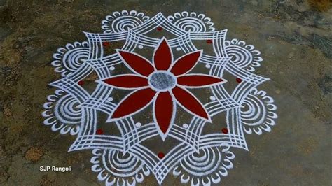 a red and white flower is on top of a cement floor with intricate ...